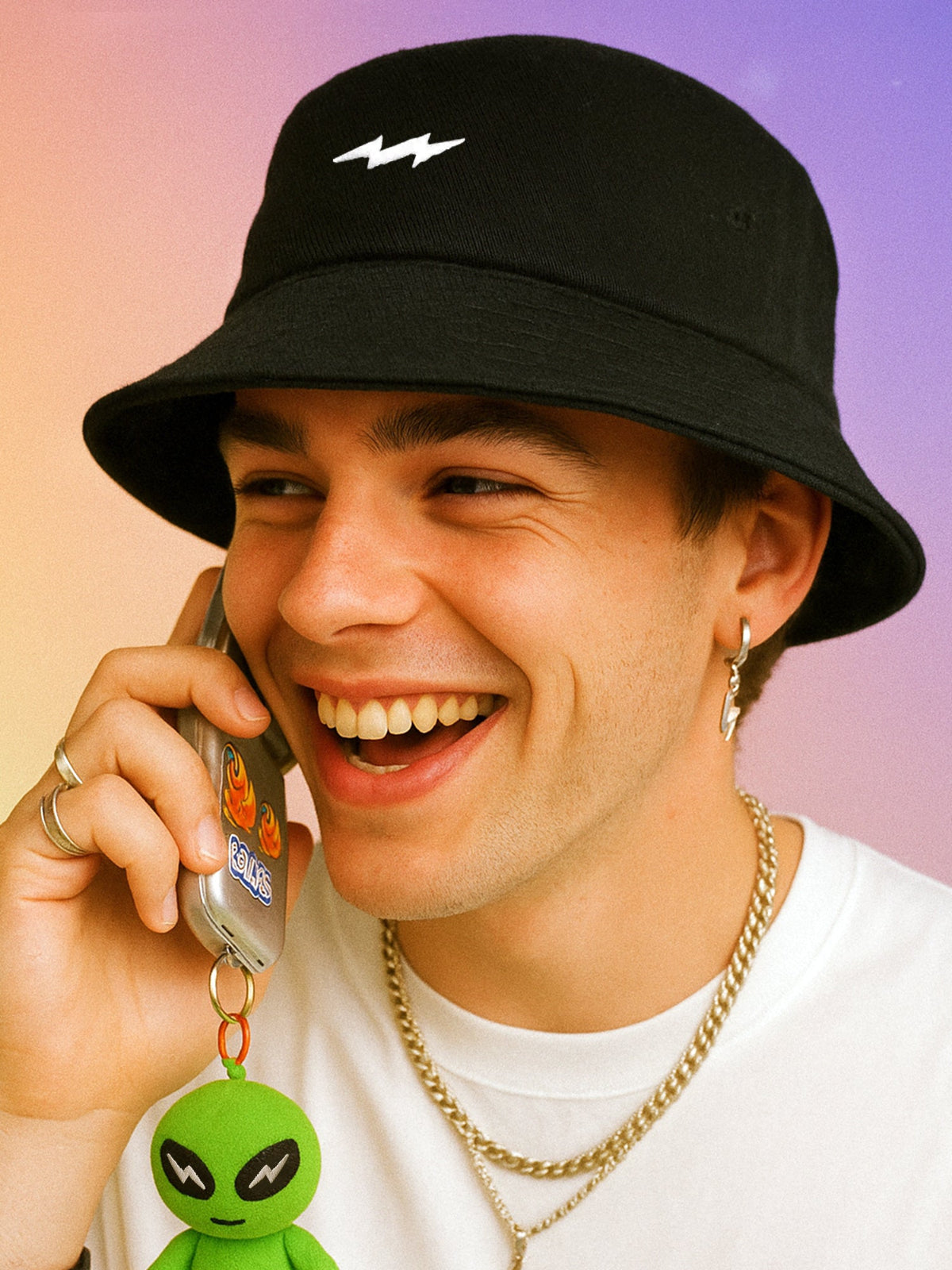 A person wearing a black bucket hat with a white lightning logo, smiling while on the phone.